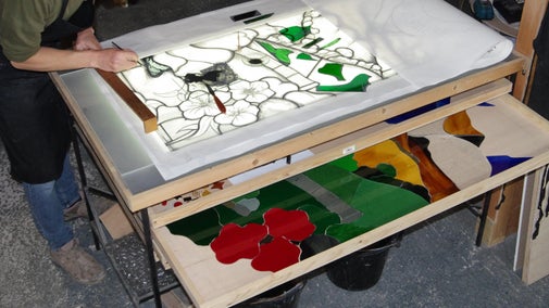 A crafts person painting a panel of stained glass